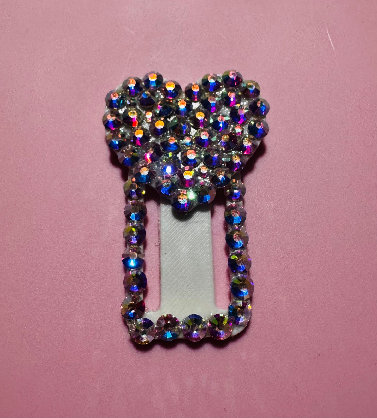 The Viva La Bombshell Burlesque TipSlider is a rectangular hair clip topped with a heart, both accented with sparkling multicolored rhinestones, shown on a pink background—a chic accessory ideal for wearable tech fans.
