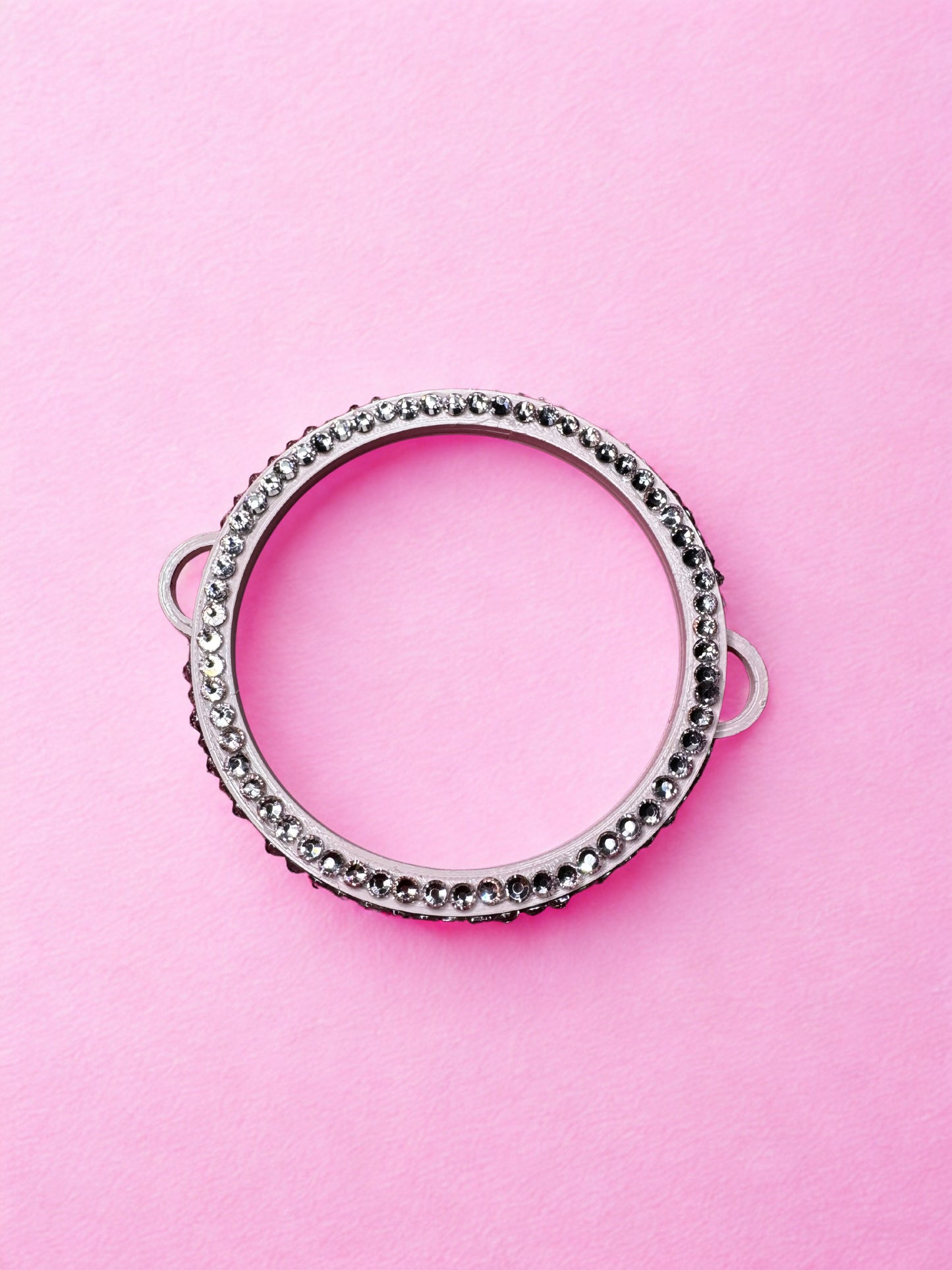 The Viva La Bombshell Burlesque Circle Bangle - Boa Attachment is a silver metal ring adorned with small decorative beads, displayed on a pastel pink background.