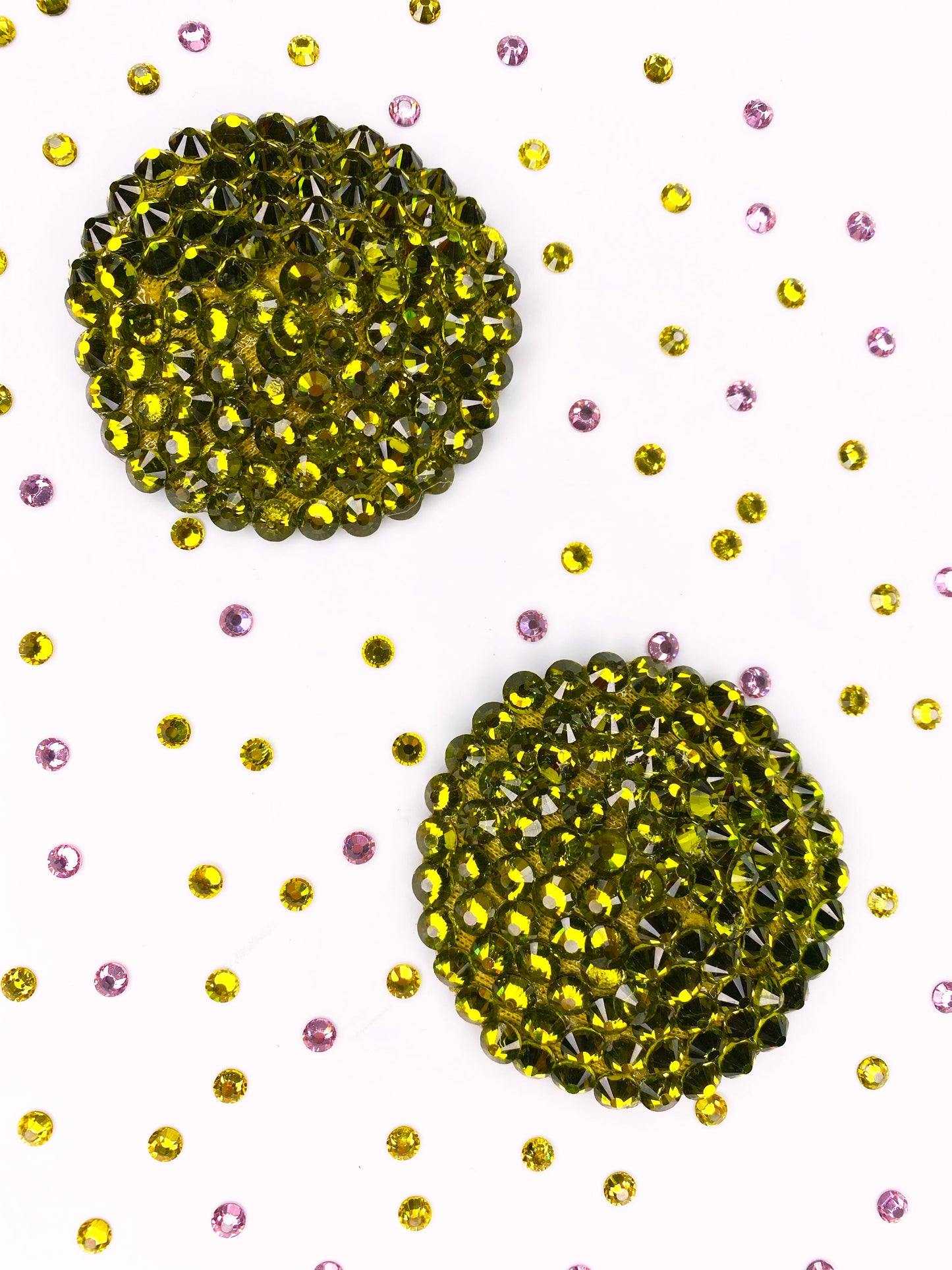 Two large Simple Rhinestone Pasties (Circle) by Viva La Bombshell Burlesque are displayed on a white background, surrounded by scattered small yellow and pink rhinestones.