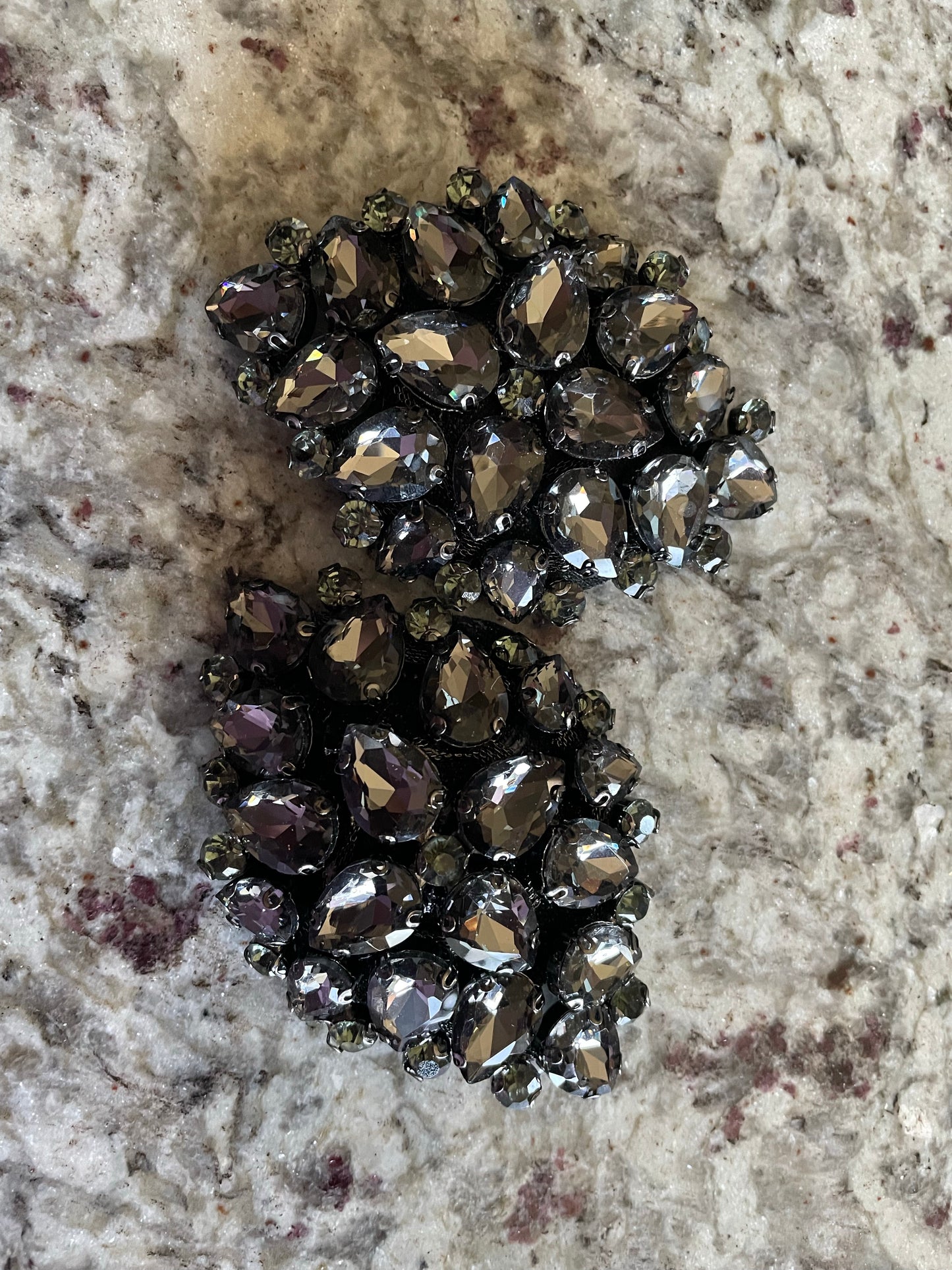 Two ornate Coal Pasties by Viva La Bombshell Burlesque, featuring dark silver rhinestones and teardrop gems, are displayed on a marbled surface with gray and red accents.