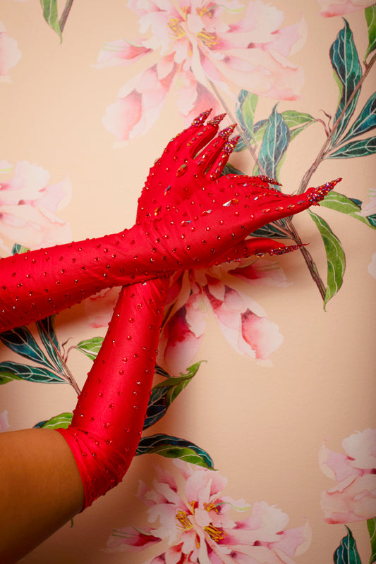 Two arms wearing Viva La Bombshell Burlesque’s Kitty Claw Gloves (AB Rhinestones) - Original are crossed at the wrists and pressed against a wall with a pink floral pattern.