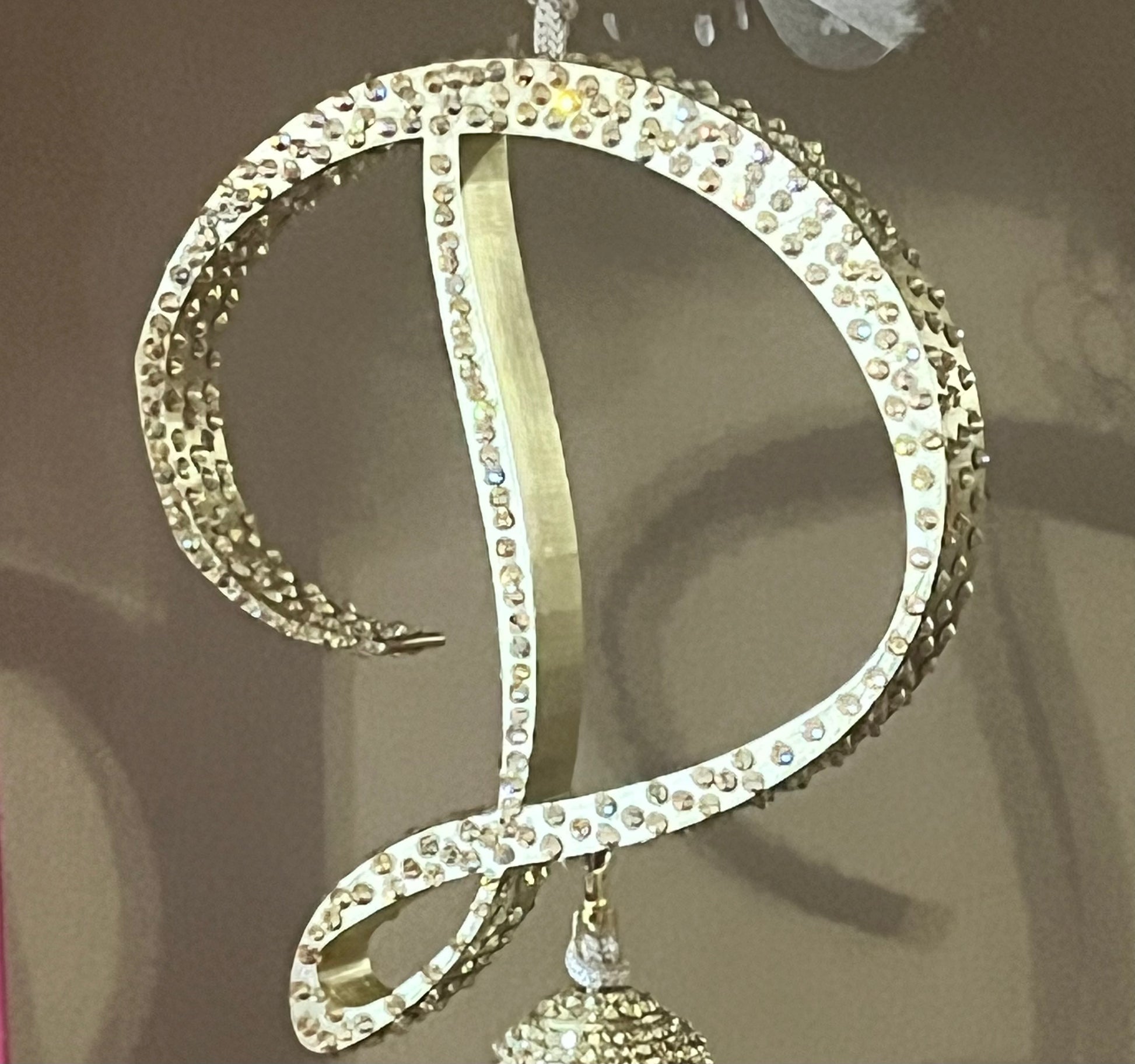 A sparkling golden "D" rhinestone charm by Viva La Bombshell Burlesque shines against a neutral background—ideal for custom boa accessories with Letter Charms - Boa Attachments.