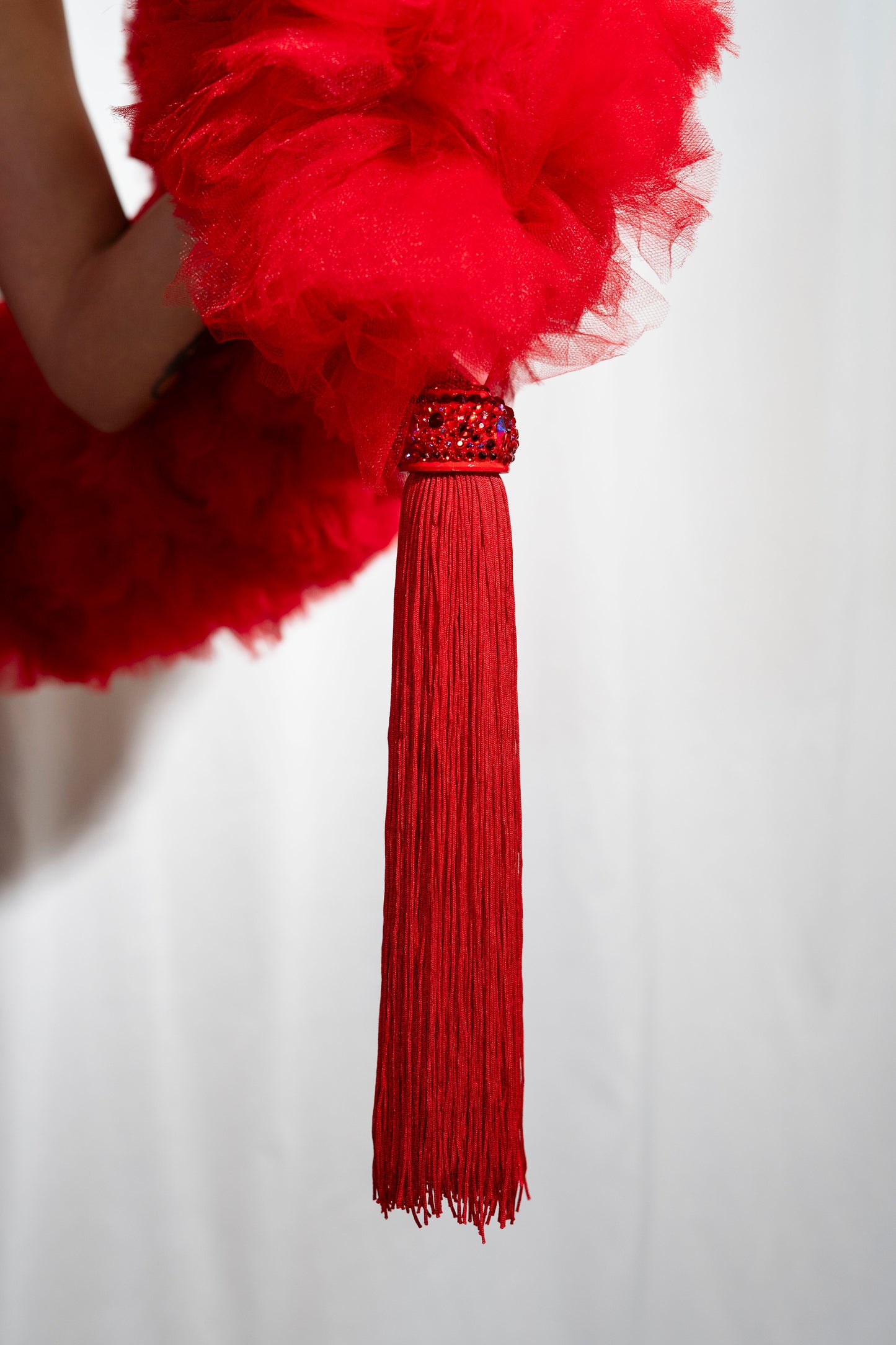 A close-up of The Dazzle - Tulle Boa by Viva La Bombshell Burlesque, featuring a red tasseled accessory with a beaded top against a white background. Each boa is made to order for a unique, elegant touch.