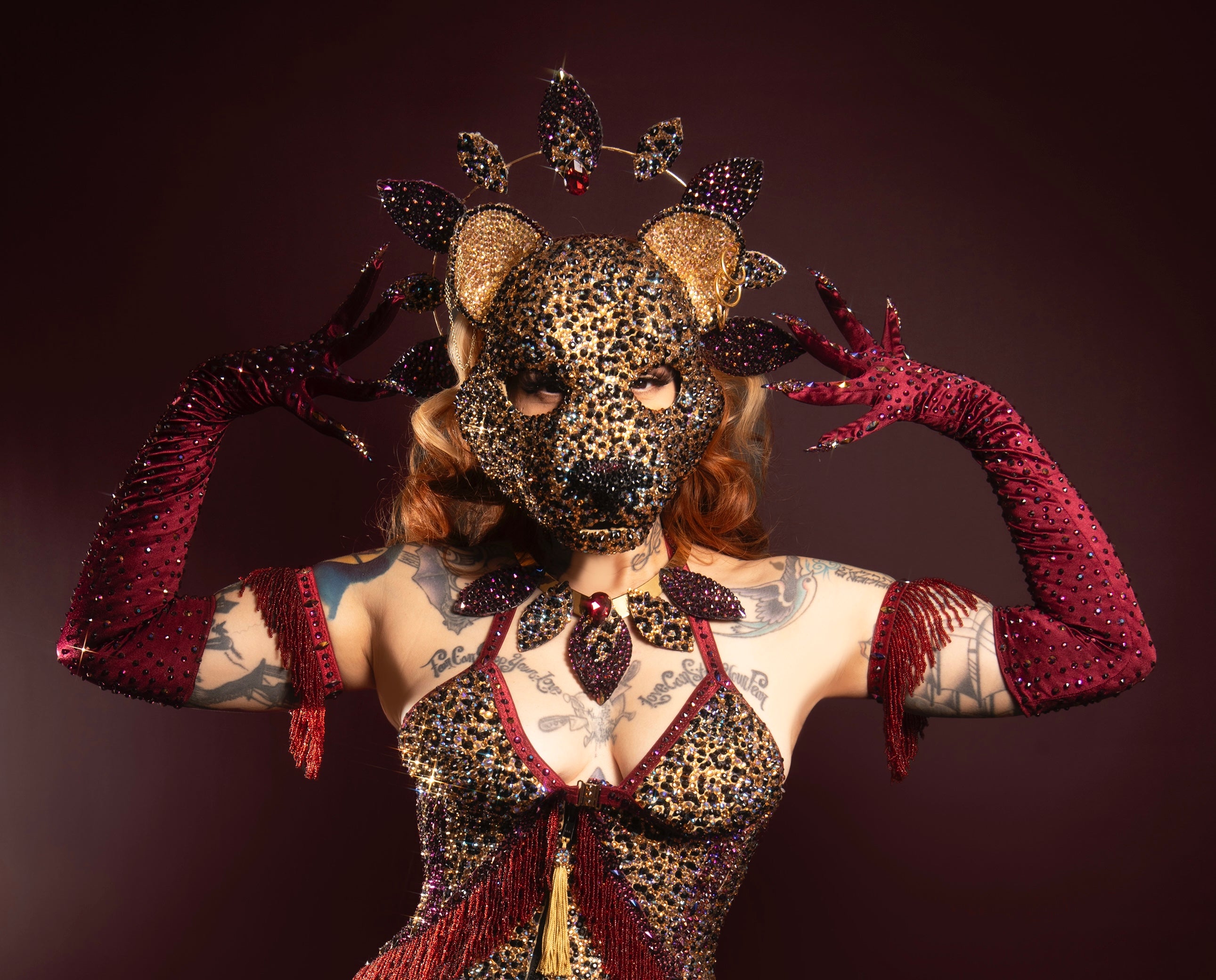 Performer wearing rhinestone leopard mask, burgundy nail gloves and rhinestone leopard burlesque costume 