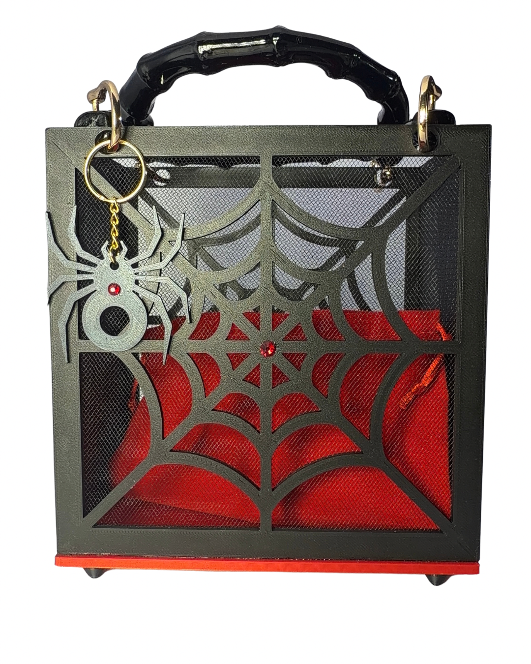 Introducing The Widow – Spiderweb Purse by Viva La Bombshell Burlesque: a black handbag adorned with a striking spiderweb motif and an attached spider keychain on the front, highlighted by sleek bamboo handles and a bold red interior pouch.
