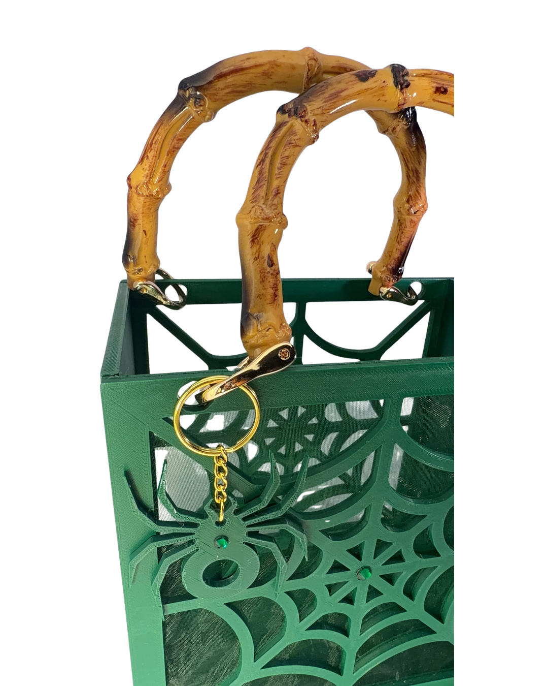 The Widow – Spiderweb Purse by Viva La Bombshell Burlesque is a green handbag showcasing a bold spiderweb design with decorative cutouts, bamboo-style handles, and a gold spider charm accent.
