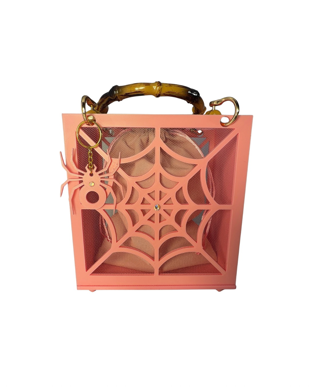 The Widow – Spiderweb Purse by Viva La Bombshell Burlesque is a square, pink 3D printed bag featuring a striking spiderweb design, bamboo handles, and a spider-shaped keychain. A beige item can be seen partially inside the purse.