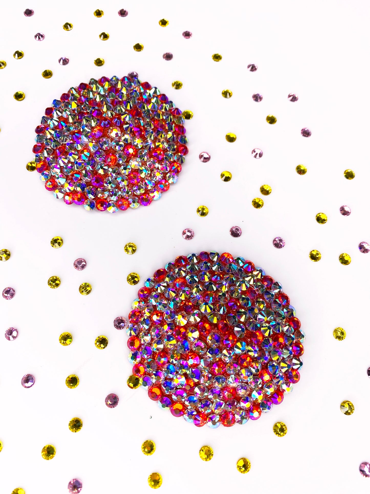 The Simple Rhinestone Pasties (Circle) by Viva La Bombshell Burlesque, featuring multicolored rhinestones, are displayed on a white background with scattered yellow and light purple rhinestones.