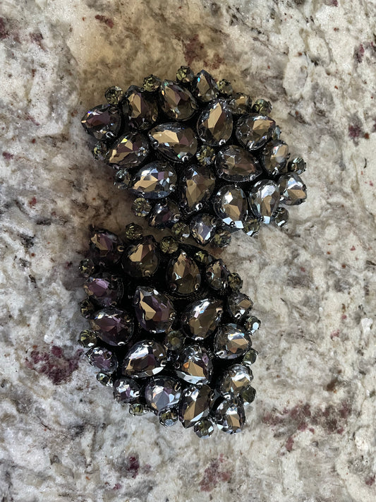 Two ornate Coal Pasties by Viva La Bombshell Burlesque, featuring dark silver rhinestones and teardrop gems, are displayed on a marbled surface with gray and red accents.